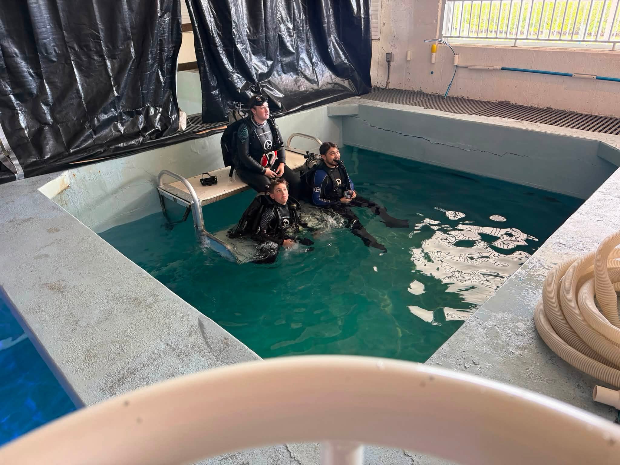 Jacob in scuba gear standing in CMA’s training pool with dive staff